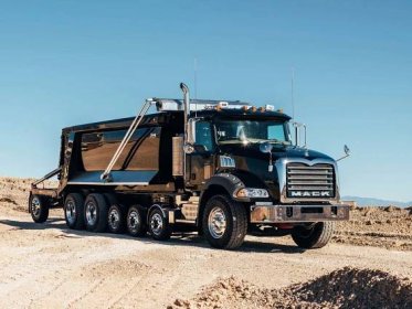 A Black Dump Truck Is Driving On A Dirt Road Wallpaper