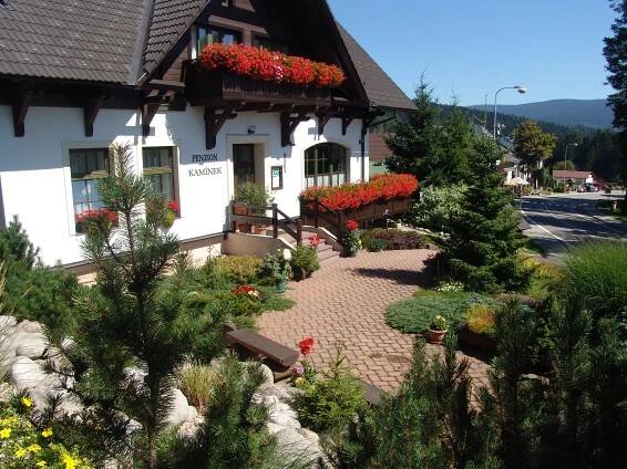 a building with flower boxes on the side of it at Penzion Kamínek in Janske Lazne