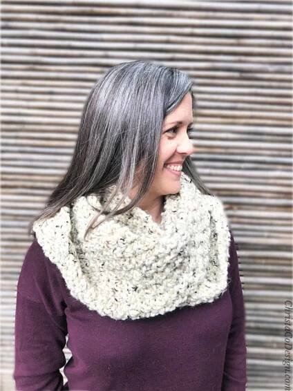 Woman smiling with head turned to the side wearing a white textured snood.