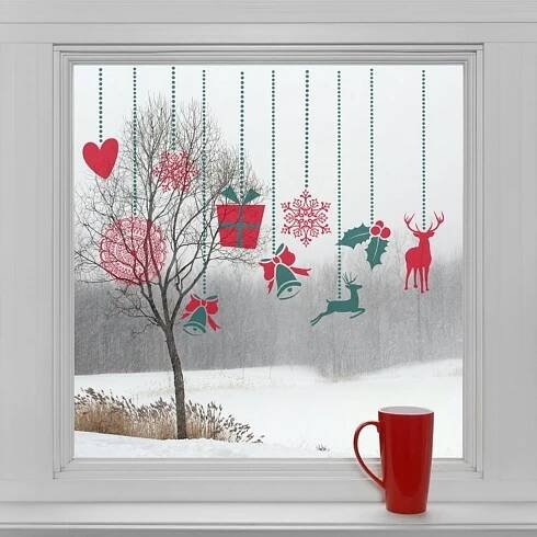 a red cup sitting next to a window with christmas decorations hanging from the windowsill