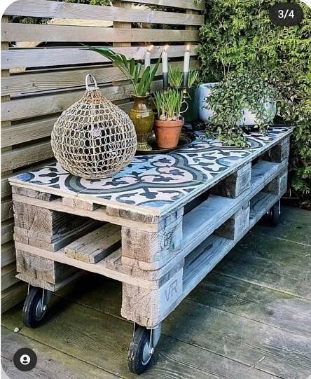 an outdoor table made out of pallets with plants on top