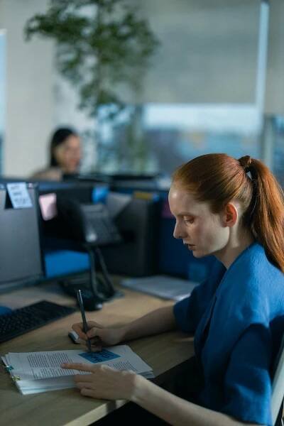 Free A professional woman concentrating on paperwork in a modern office setting. Stock Photo