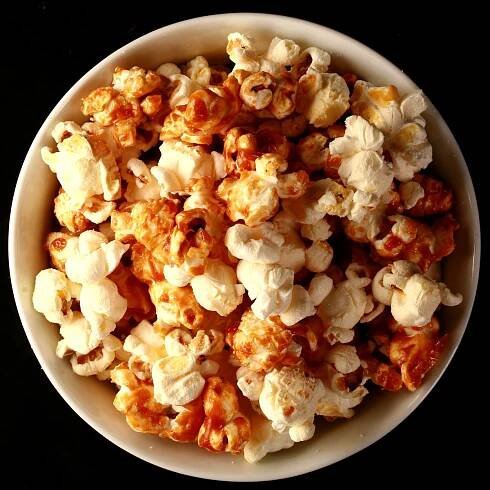 Close up photo of a bowl of two-tone popcorn: Maple White Cheddar Popcorn. Half of the popcorn is covered with maple caramel, the other half is white - white cheddar.