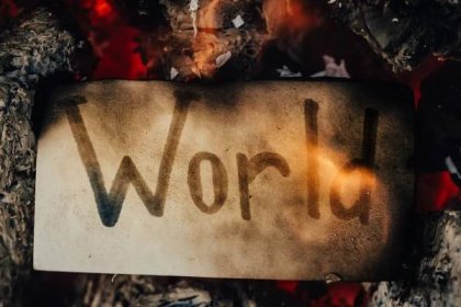 TJe world "WORLD" written on a dirty piece of paper surrounded by flames and disaster