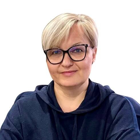 Osoba s krátkými blond vlasy a černými brýlemi, oblečená v tmavě modré mikině s kapucí, sedí čelem k fotoaparátu na prostém bílém pozadí a je připravena sdílet své postřehy na Fóru o novém jídle.