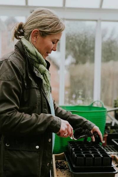 Clare Foster adding compost to a seed tray in her greenhouse