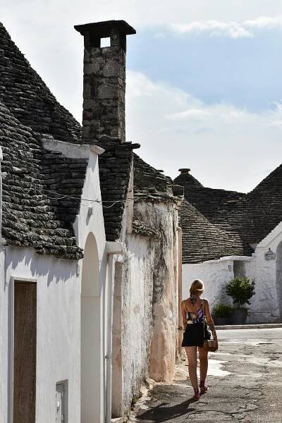 bezplatná Žena procházející kolem ikonických trulli domů v půvabném městečku Alberobello v Itálii. Základová fotografie