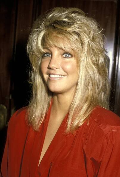 Person with voluminous layered hairstyle, wearing a red blouse, smiling at the camera