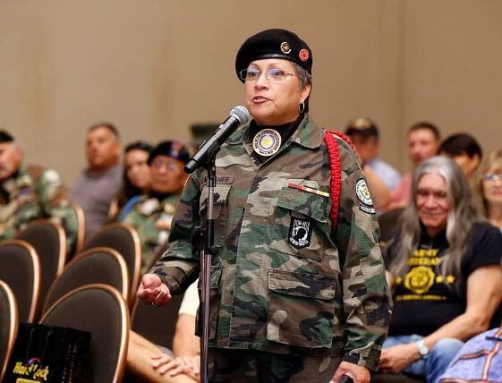 Marine Corps veteran Debra Wilson in uniform standing up in front of a microphone addressing a speaker panel.