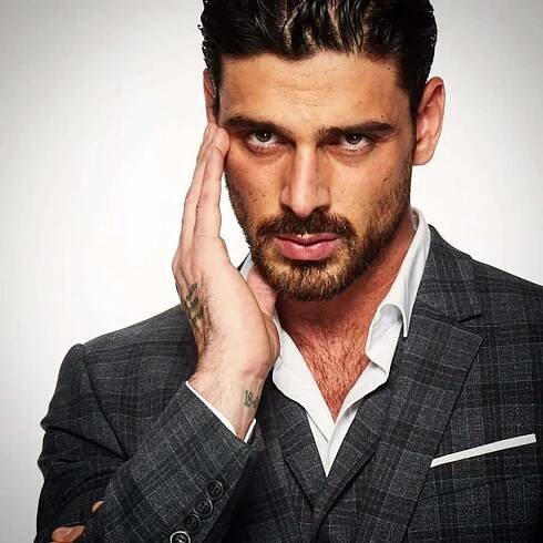 A Man In A Suit With His Hand On His Face