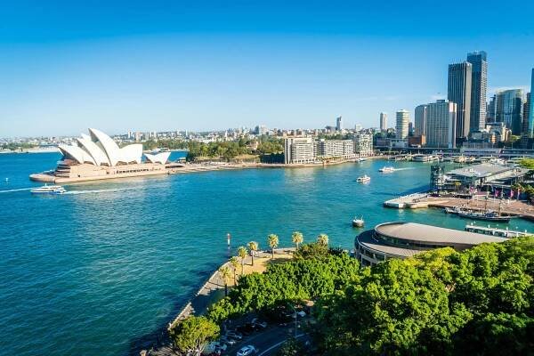 Sydney Opera House and harbor with city skyline in the background.