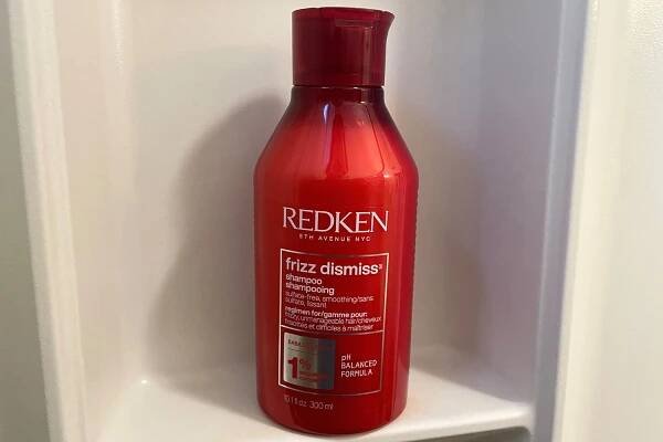 Redken Frizz Dismiss Shampoo placed on a cupboard