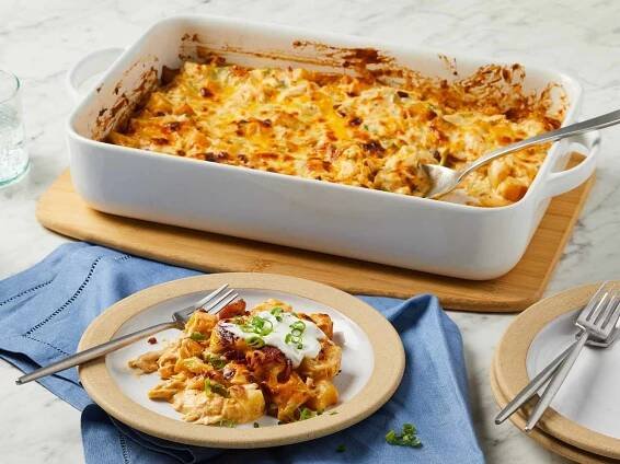 close up view on a serving of loaded chicken and potato casserole on a plate with remaining in the casserole dish.