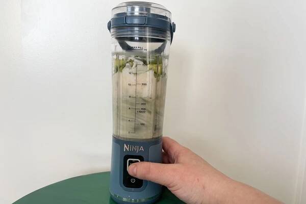 A hand holding the the Ninja Blast Portable Blender while it's blending
