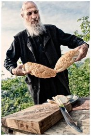 Imereti, Georgia. The Georgian monk Maxime Kavtaradze cuts bread on a rock in front of his house.