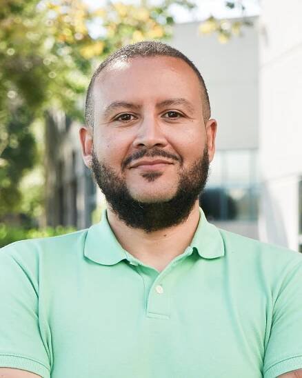 miguel mendoza wearing green collar shirt headshot with arms crossed