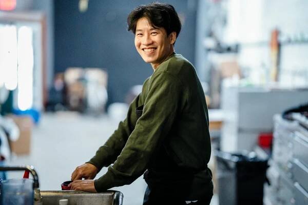 Free Portrait of a smiling man in a casual indoor workshop setting. Stock Photo