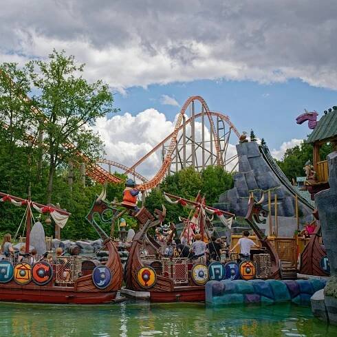 Wikinger-Schiffe treiben im Freizeitpark Plopsaland vor einer Achterbahn im Wasser.