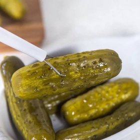 close up of pickle picker holding onto a pickle