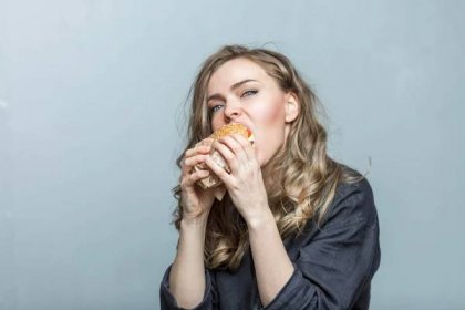 Young Woman Eats Hamburger With Appetite Fast Junk Delicious Food Grey Background Closeup