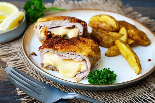 Cordon Bleu angeschnitten mit Kartoffelecken auf einem Teller.