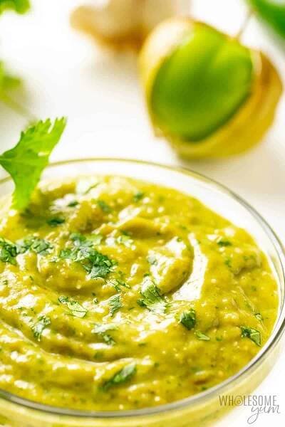 Close up of tomatillo avocado salsa in a bowl with herbs garnishing.