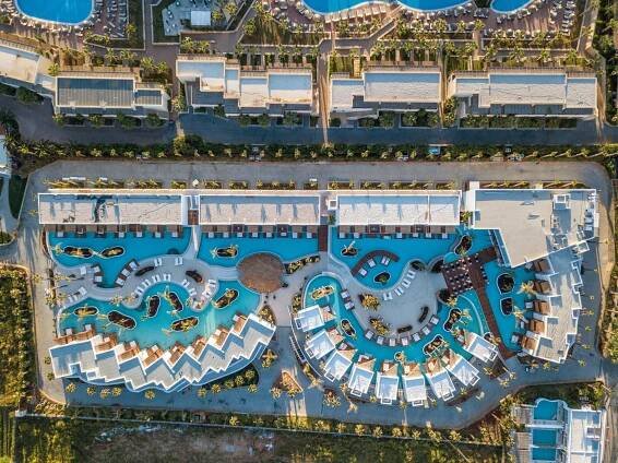 Stella Island Luxury Resort & Spa (Adults Only) Hersonissos  Exterior photo This is an aerial view of a luxurious resort complex. The resort features multiple buildings, likely hotel accommodations, arranged in a somewhat linear fashion along a road. 

The most prominent feature is a large, elaborate swimming pool area. It's
