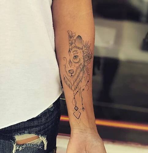 a woman's arm with a wolf tattoo on the left side of her hand