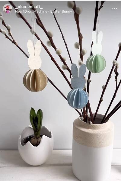 two vases filled with different types of paper ornaments hanging from the top of them
