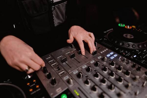 Free Close-up of DJ hands operating a mixing panel in a dark setting for dynamic sound control. Stock Photo