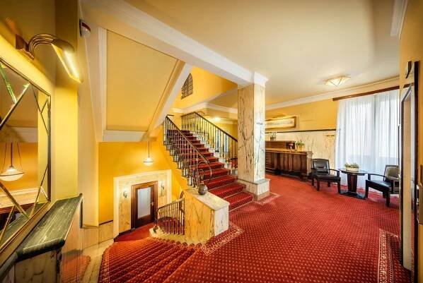 an old building with stairs and a room with chairs at Esplanade Hotel Prague in Prague