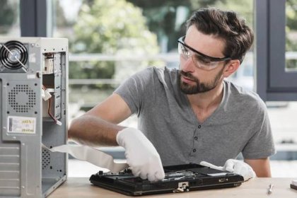 Male technician examining broken laptop in workshop