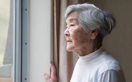 Starší žena při pohledu z okna svého domova