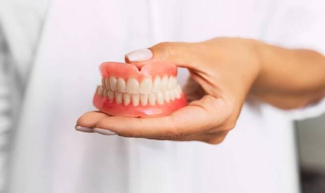 Woman holds dentures