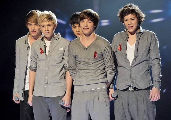 a group of young men standing next to each other holding microphones