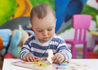 Stáhnout - Malé batole, nebo dítě děti hrát s tvary puzzle na nízkém stolku v místnosti barevné děti do školky nebo školky. — Stock obrázek