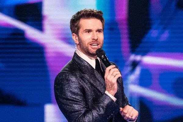 Man in a sparkly suit speaking into a microphone.