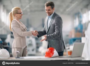 Stáhnout - Podnikatel a obchodnice si potřásají rukama v továrně. Architekti pracující na projektu. — Stock obrázek