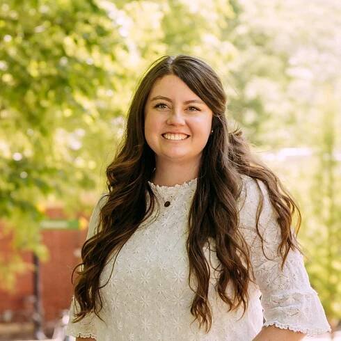 A woman in a white dress is smiling for the camera.