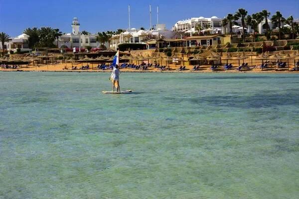 Šarm aš šajch, Egypt - 14 března 2018. Řadu slaměné slunečníky k ochraně proti přehřátí na písečné pláži proti modré obloze a modré moře. Pojem letní dovolená, Turistika, cestování. — Stock obrázek