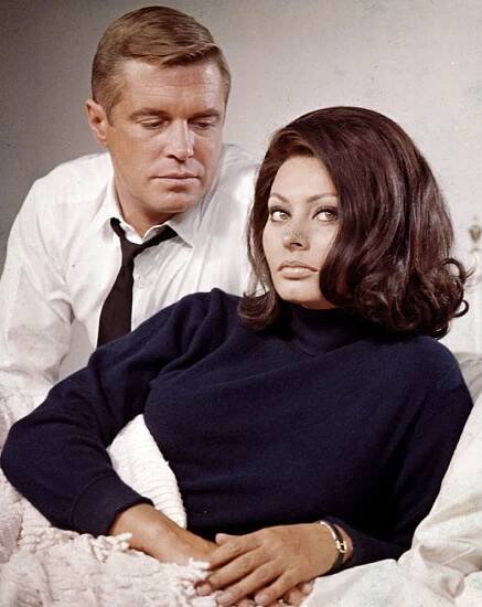 a man standing next to a woman on top of a bed