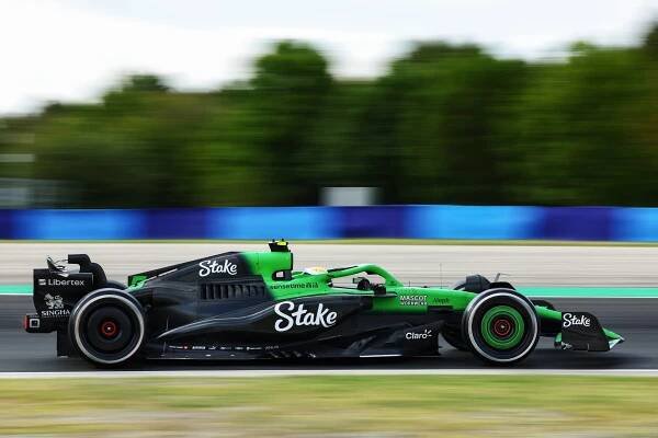 A green and black Formula 1 car passes in front of a blurry background. 
