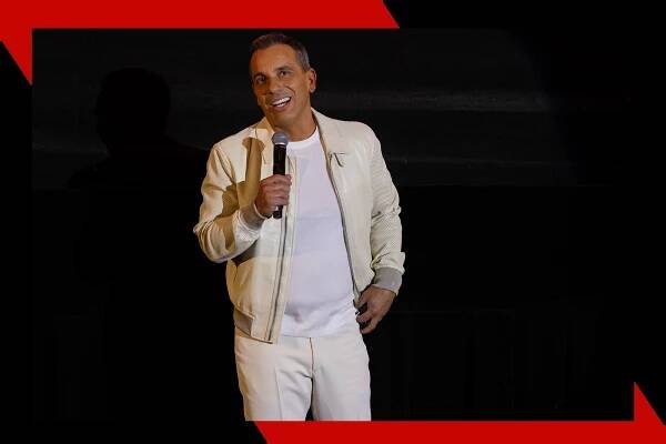 Sebastian Maniscalco performs in a white suit.