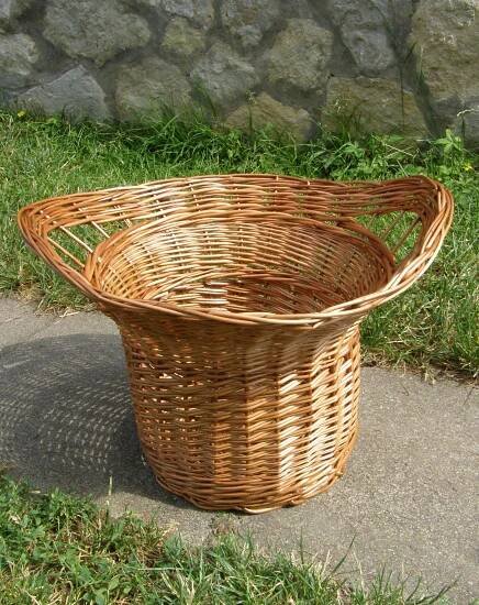 a wicker basket sitting on the ground in front of a stone wall and grass