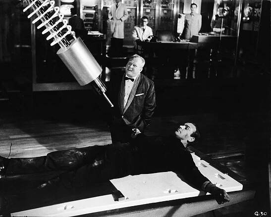 Villain Auric Goldfinger (Gert Frobe) laughs as British agent James Bond (Sean Connery) lies strapped to a table beneath a laser weapon in a still from the film, ‘Goldfinger,’ directed by Guy Hamilton, 1964. (Photo Credit: United Artists/Courtesy of Getty Images)