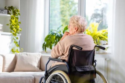 Lonely senior woman sitting in wheelchair in her house