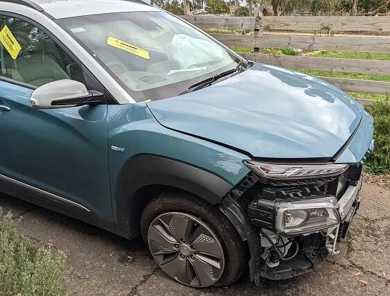 Crashed Kona Electric sitting in my driveway with the front smashed in and a damaged flat tyre