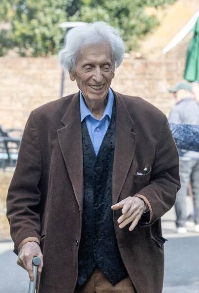 Tom Baker, actor known for Doctor Who, smiling while walking with a cane.