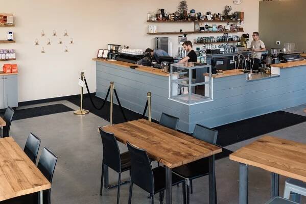 Three people work behind the counter in a coffee shop.