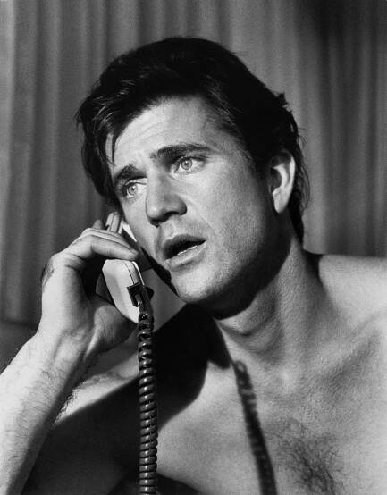 a shirtless man talking on a telephone